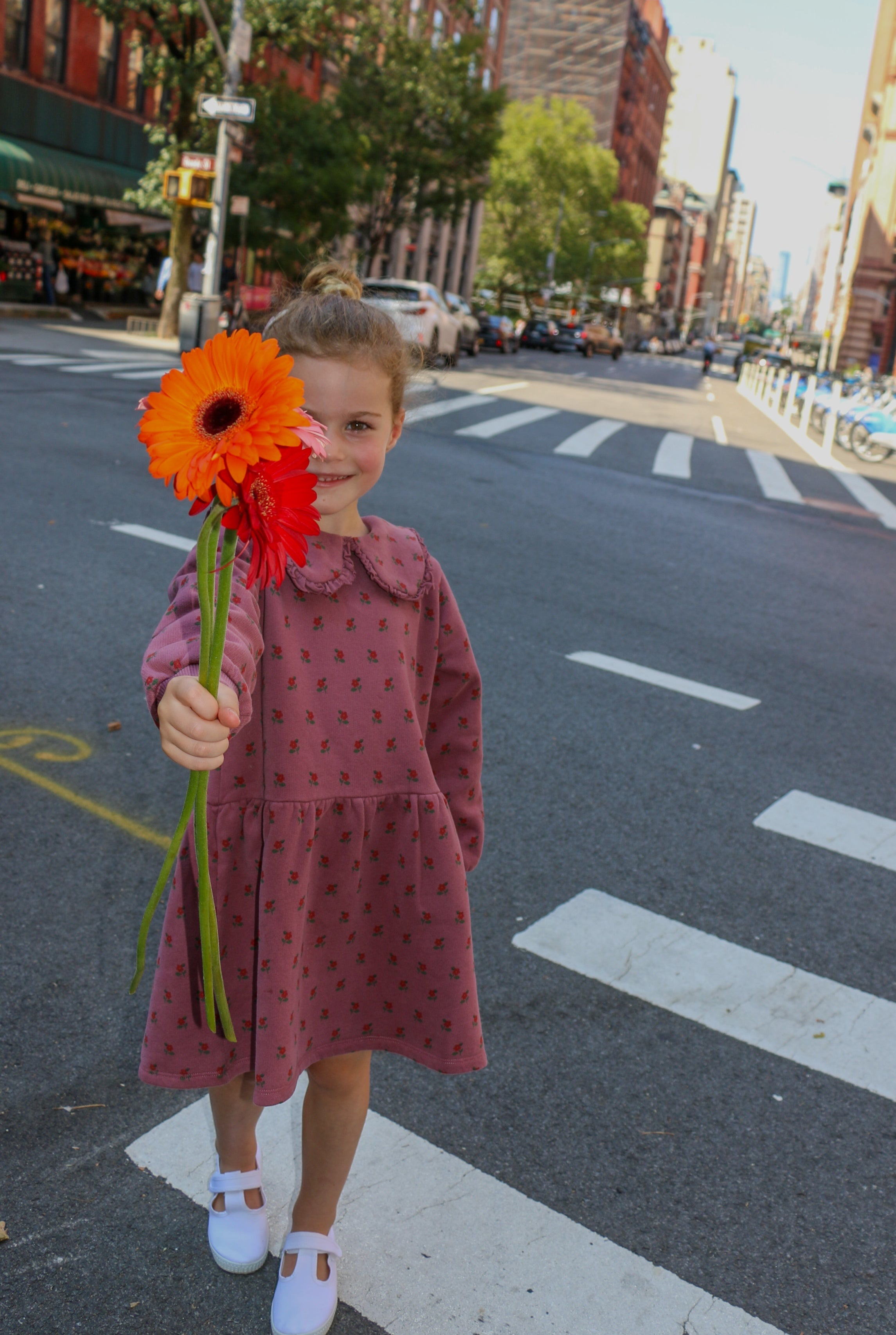 girl wearing fall floral dress holding a flower in nyc streets