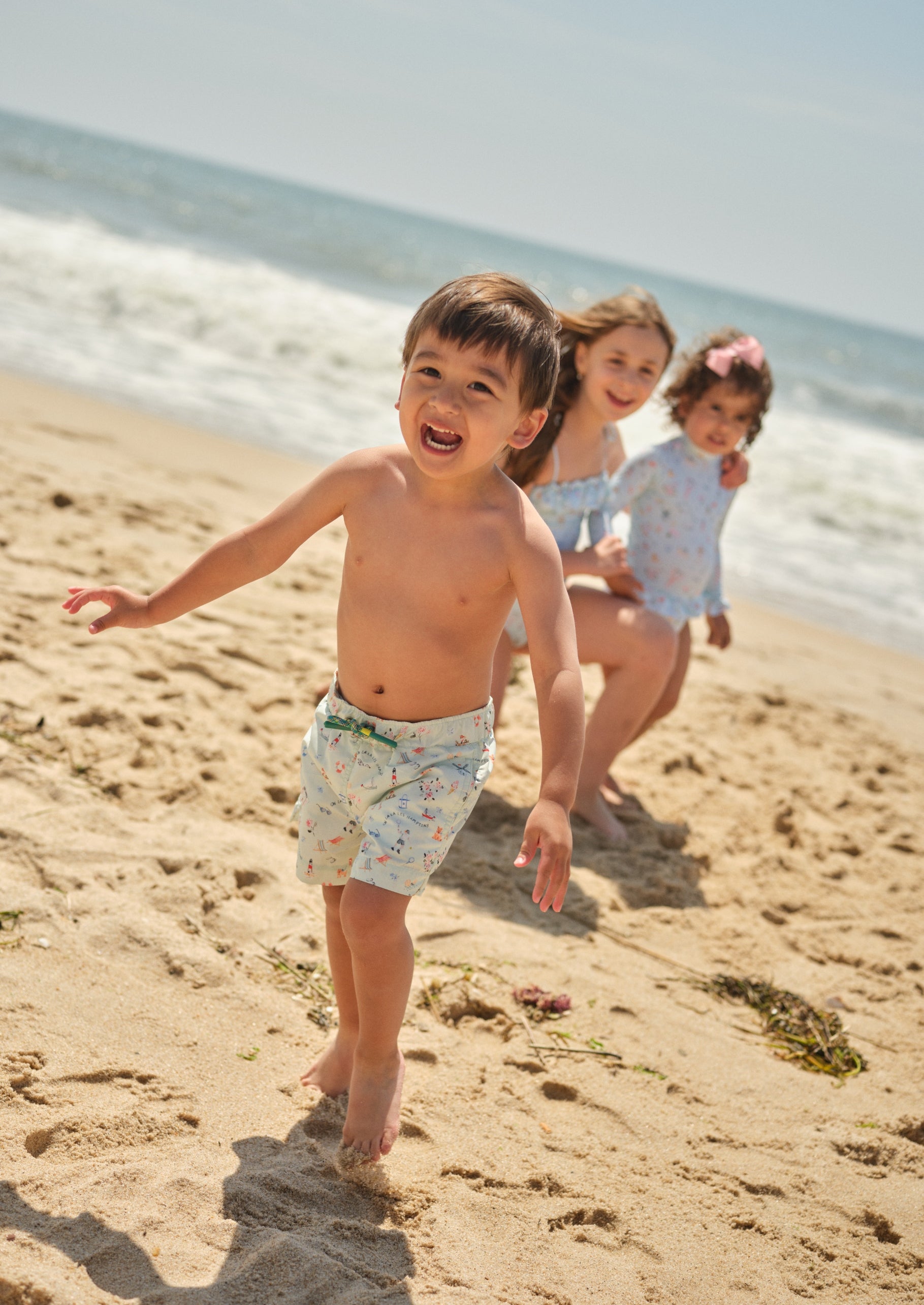 boy running on the beach in a swimsuit