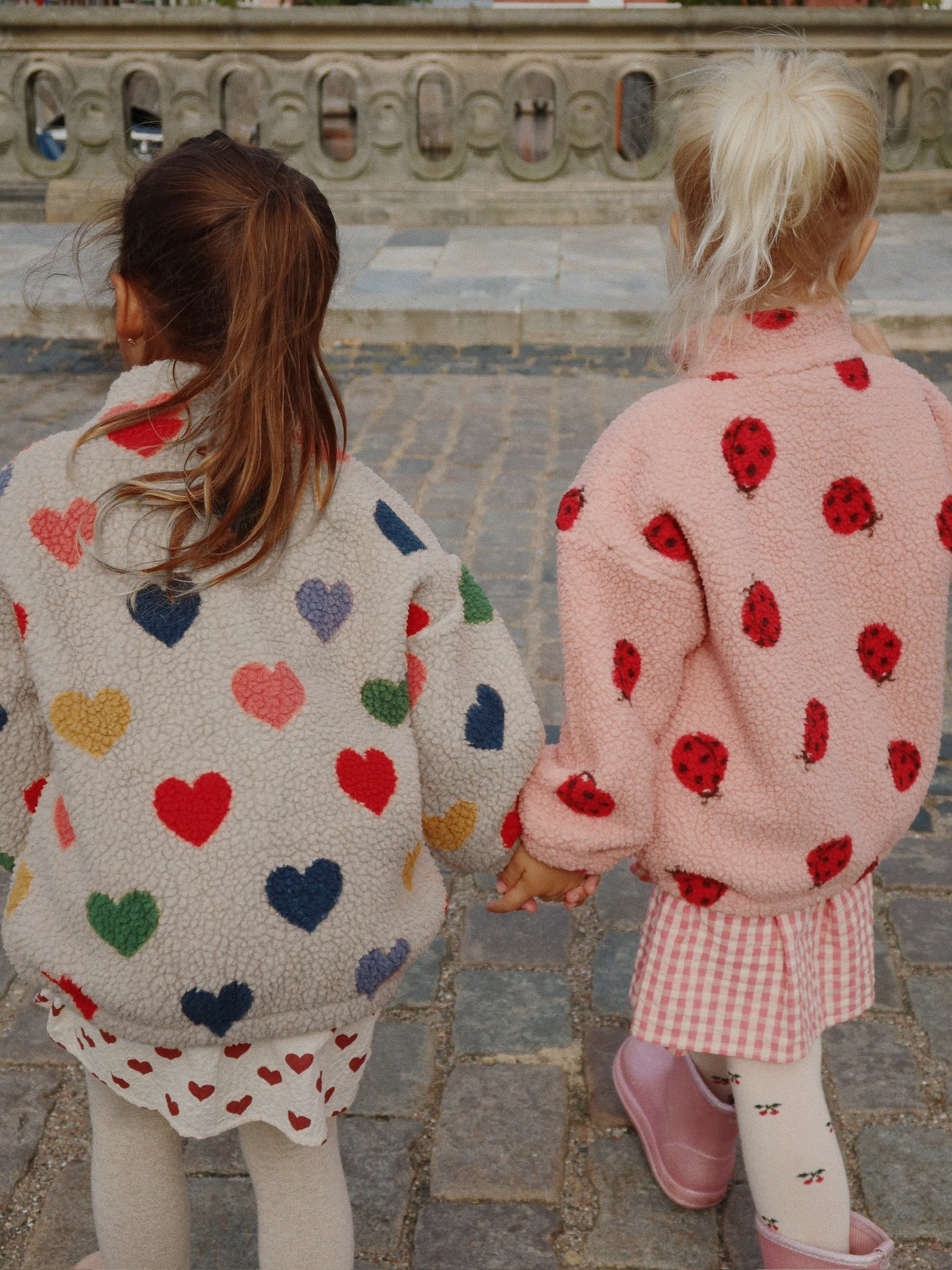 two girls wearing konges slojd outerwear holding hands