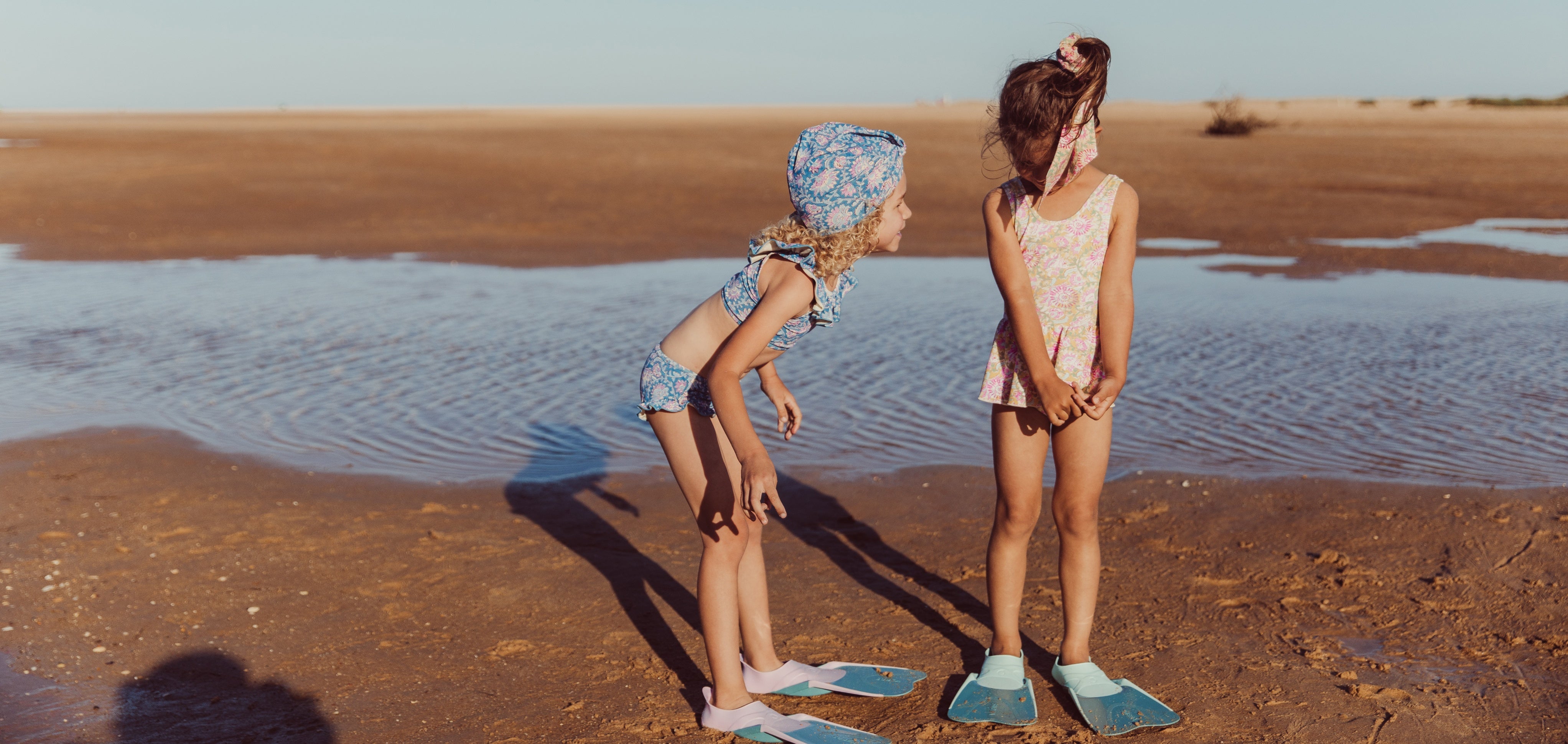 2 girls on the beach wearing swimsuits