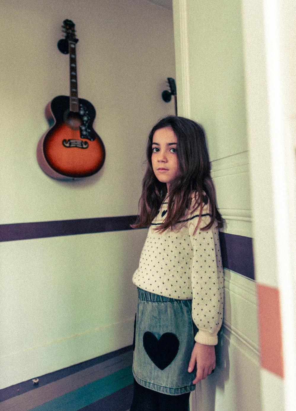 young girl wearing white heart sweater with denim skirt