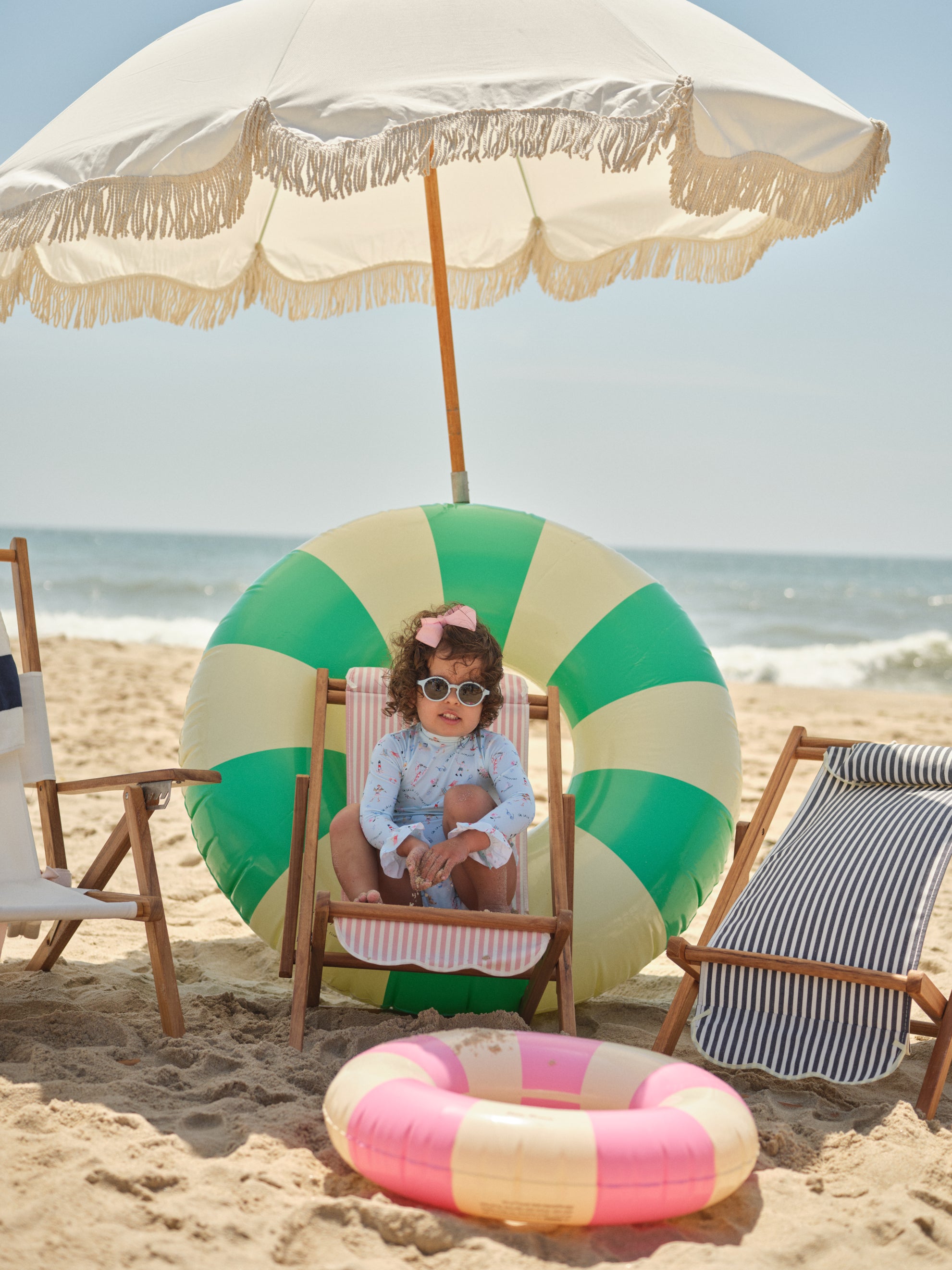 little girl sitting on the beach under an umbrella