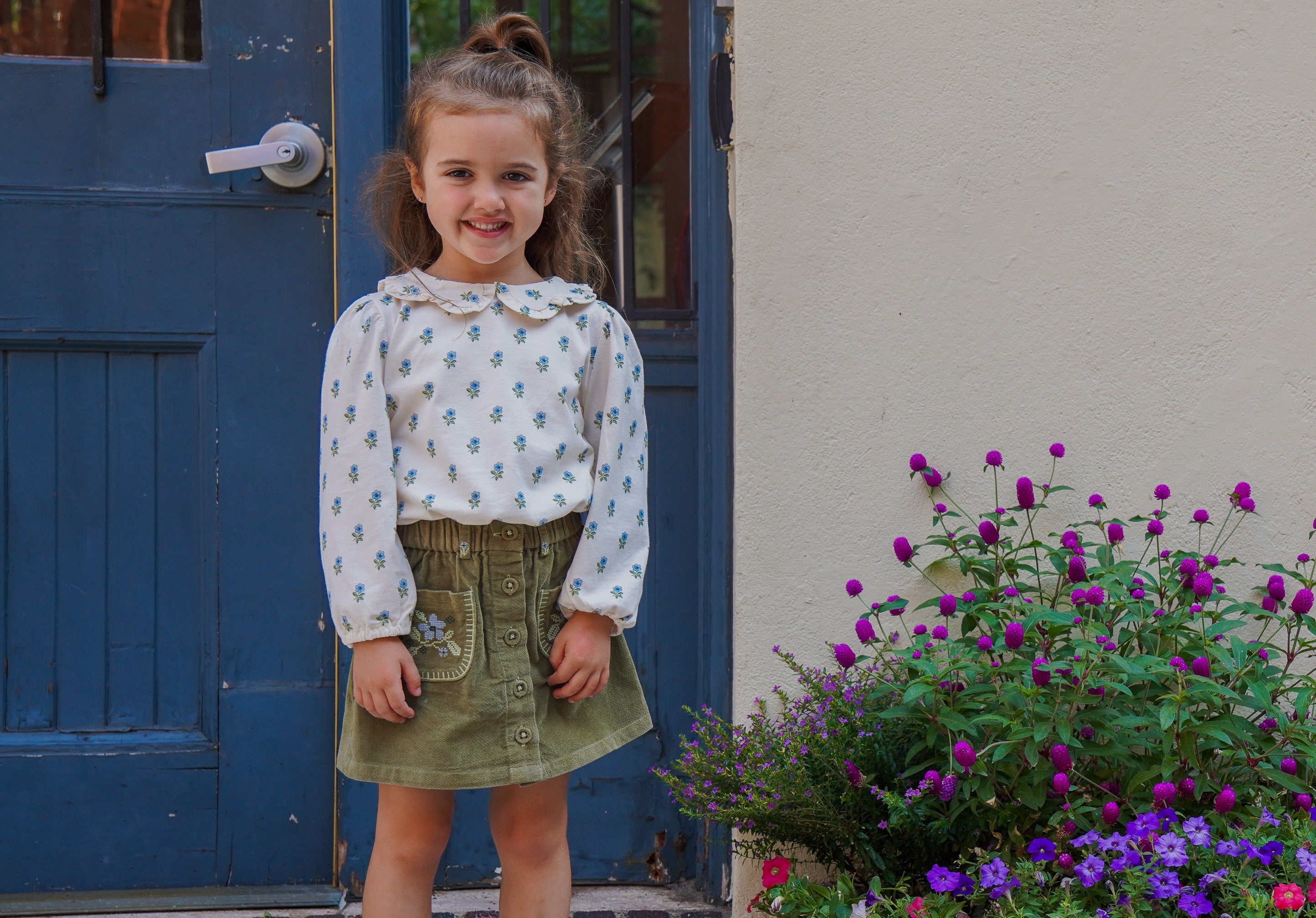 girl wearing floral shirt and green corduroy skirt