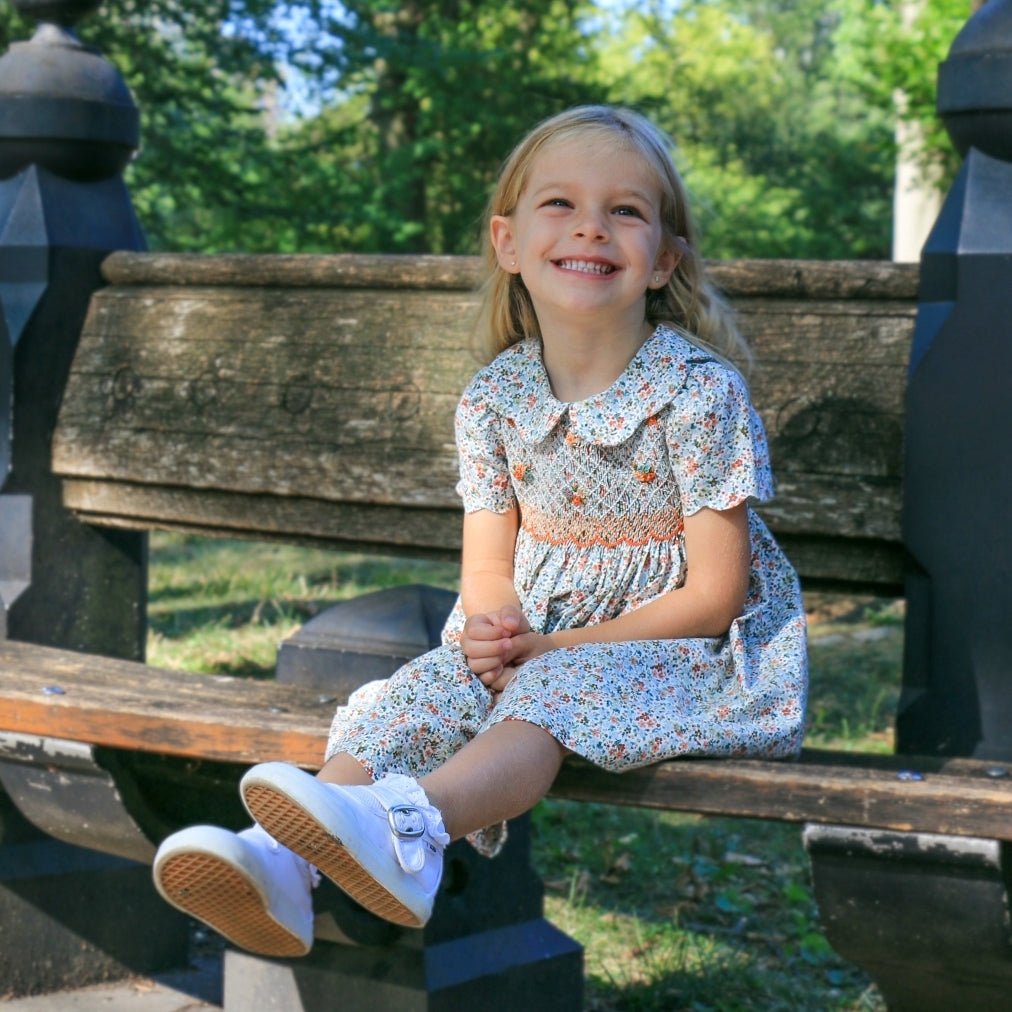 girl wearing floral dress on park bench