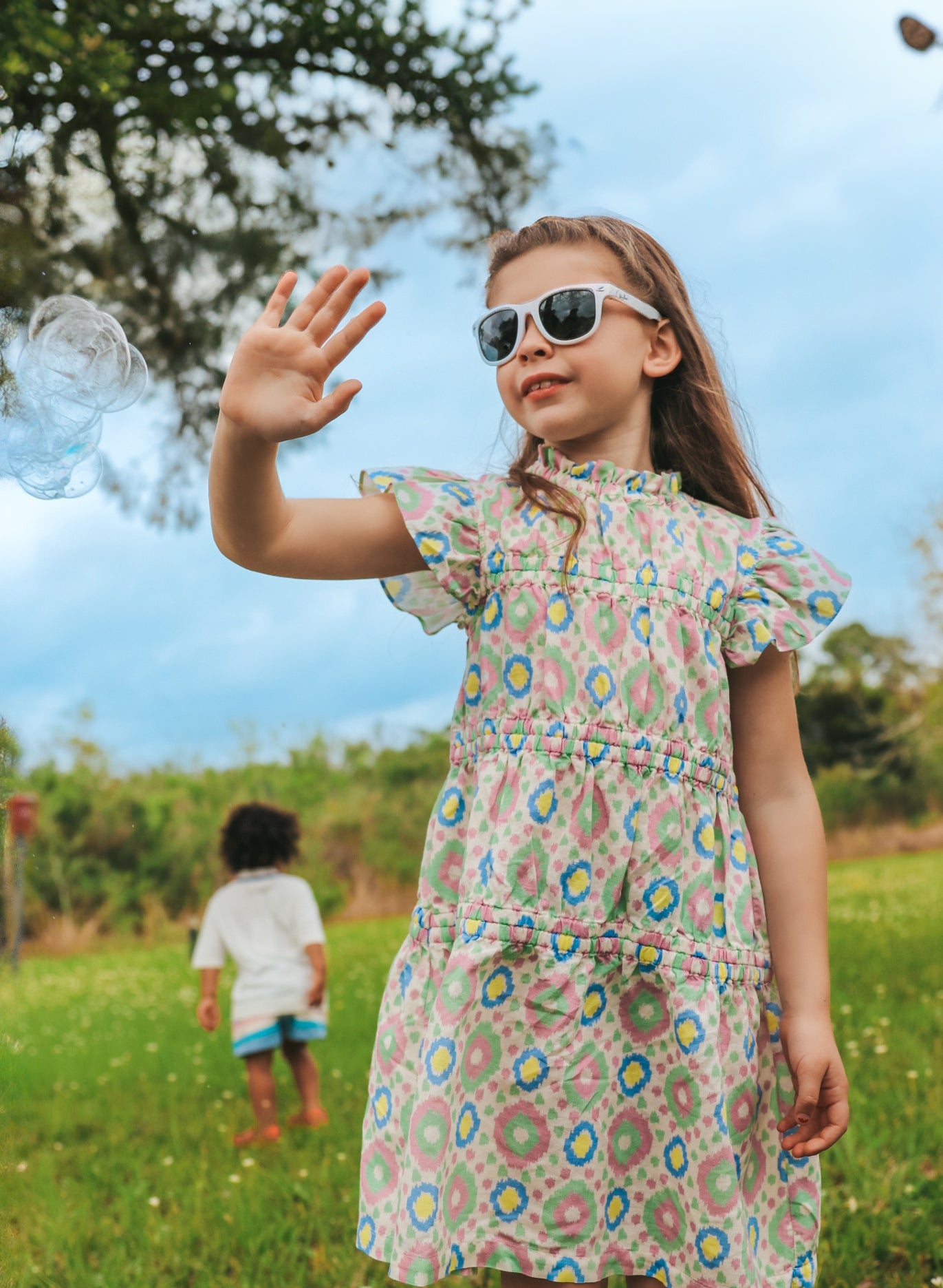 girl with hand up standing in field