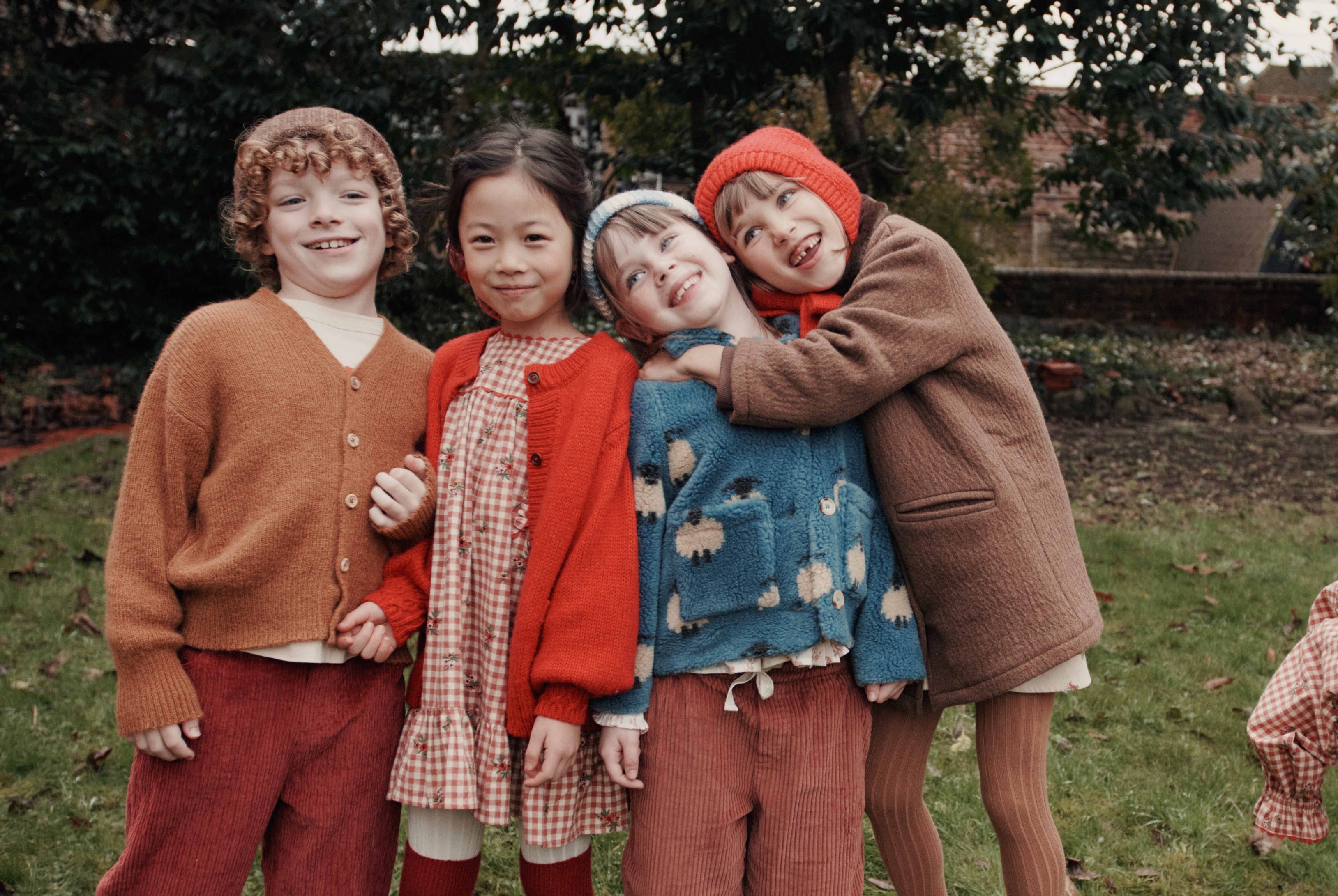 4 kids smiling and hugging eachother in a grassy field
