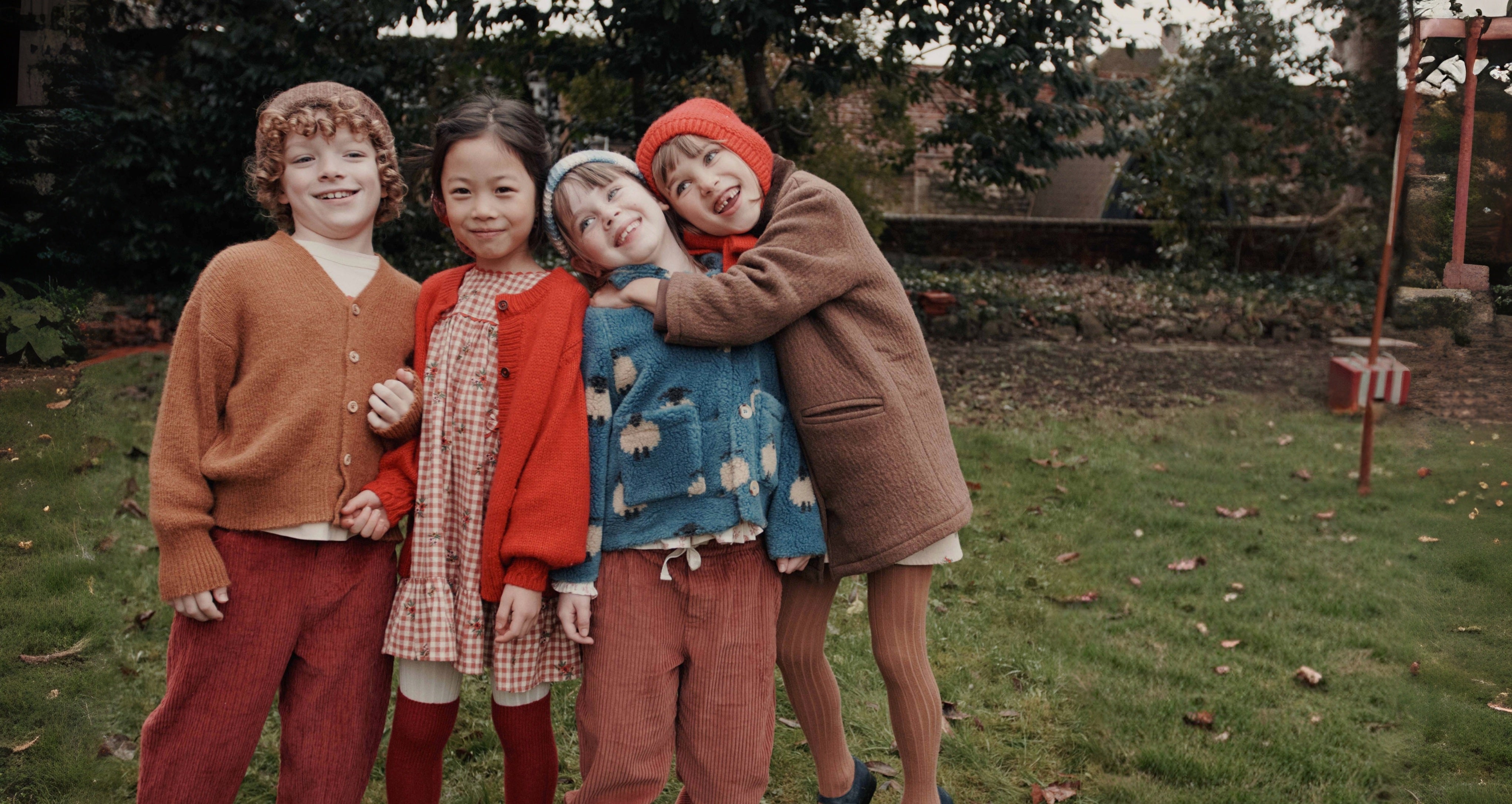 kids wearing fall outfits hugging eachother in a field