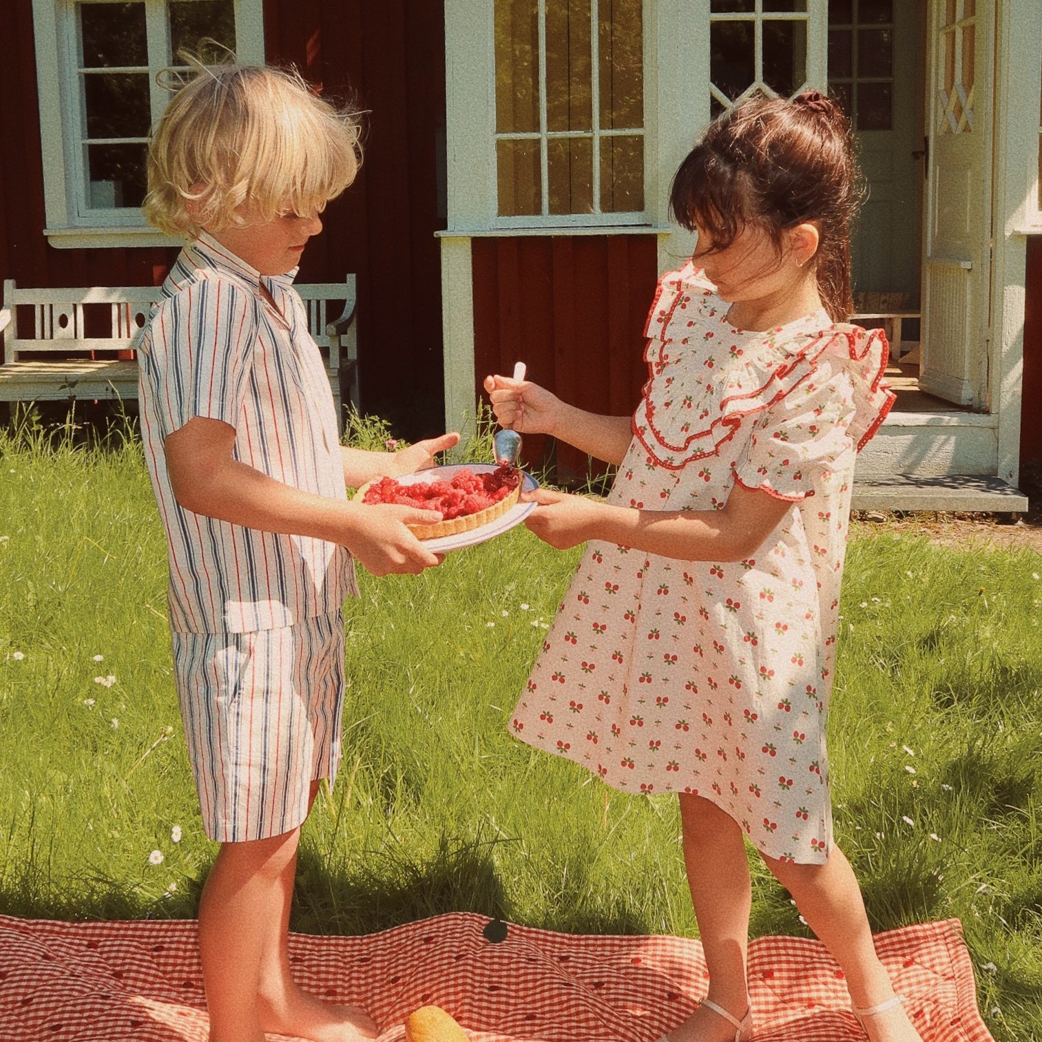 girl and boy sharing a pie at a picnic