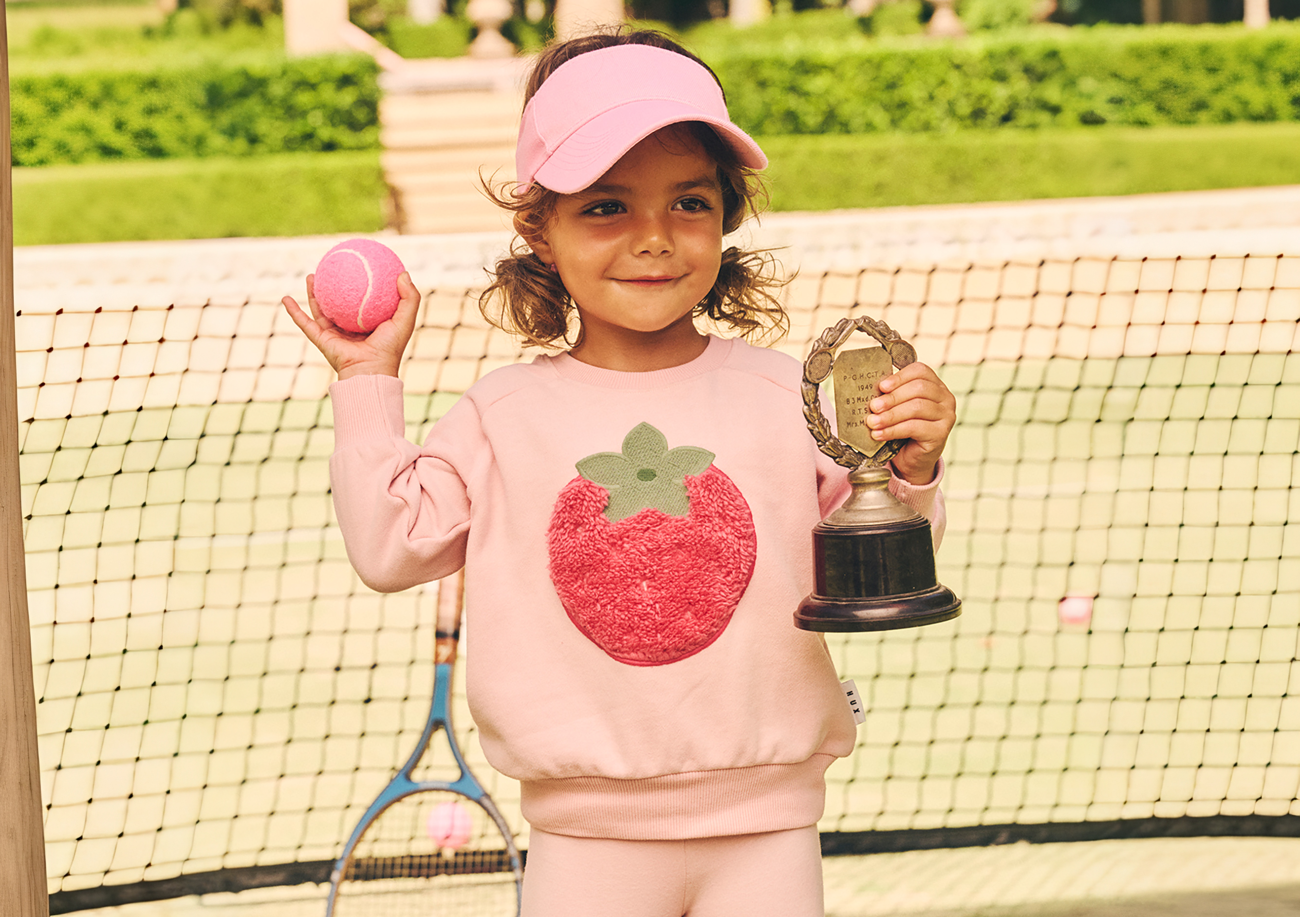 girl in pink sweatsuit holding trophy