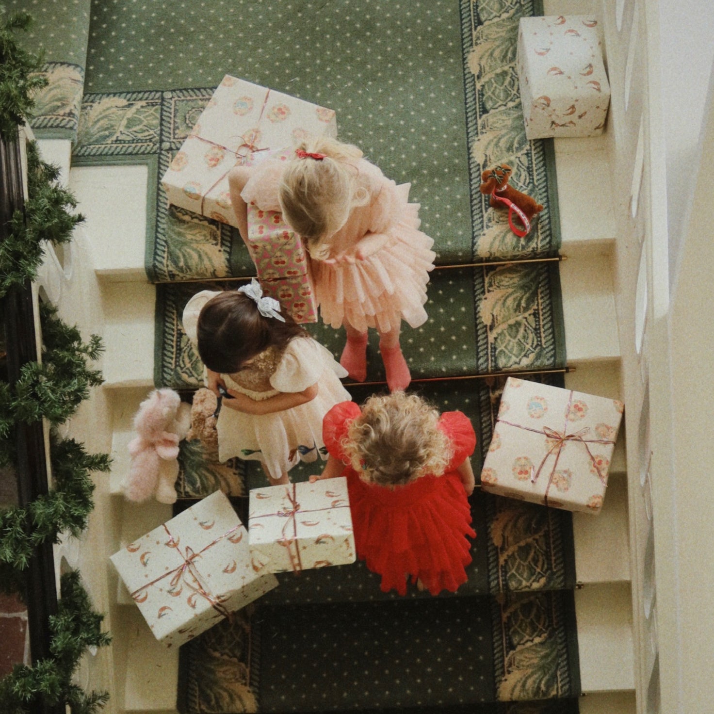 kids in holiday dresses on stairs holding gifts