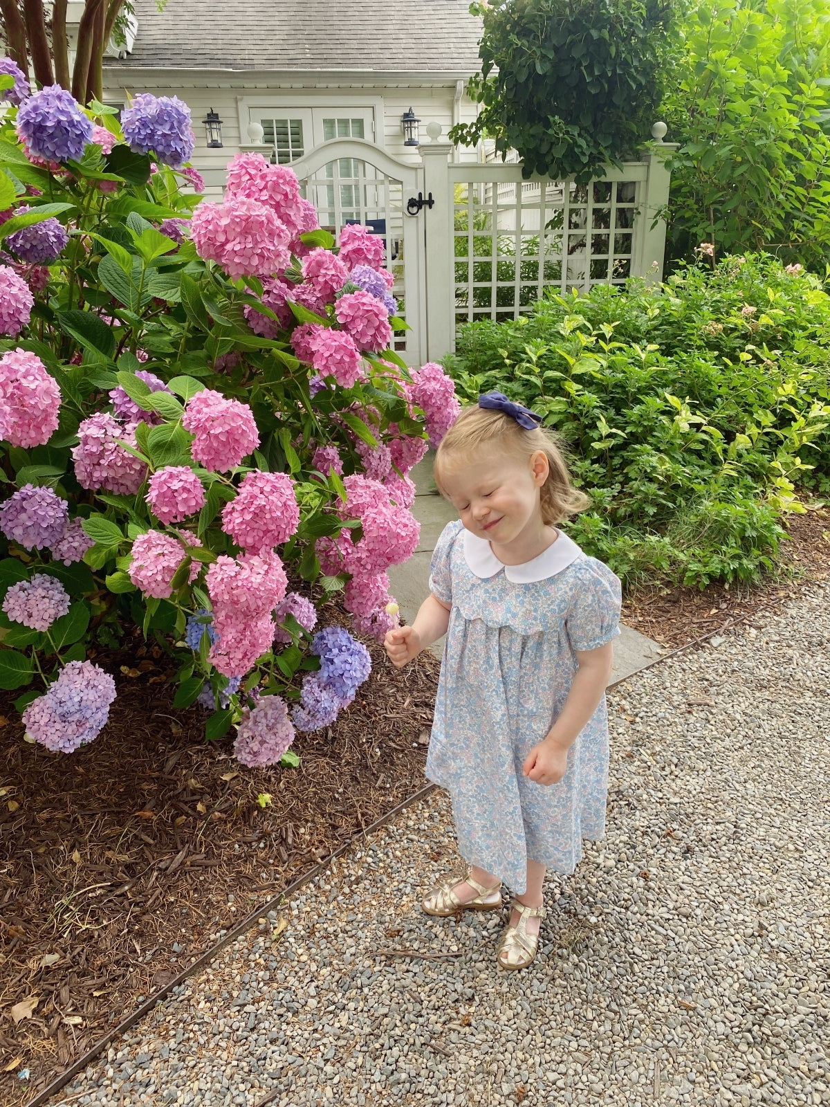 little girl in front of flowers wearing floral dress