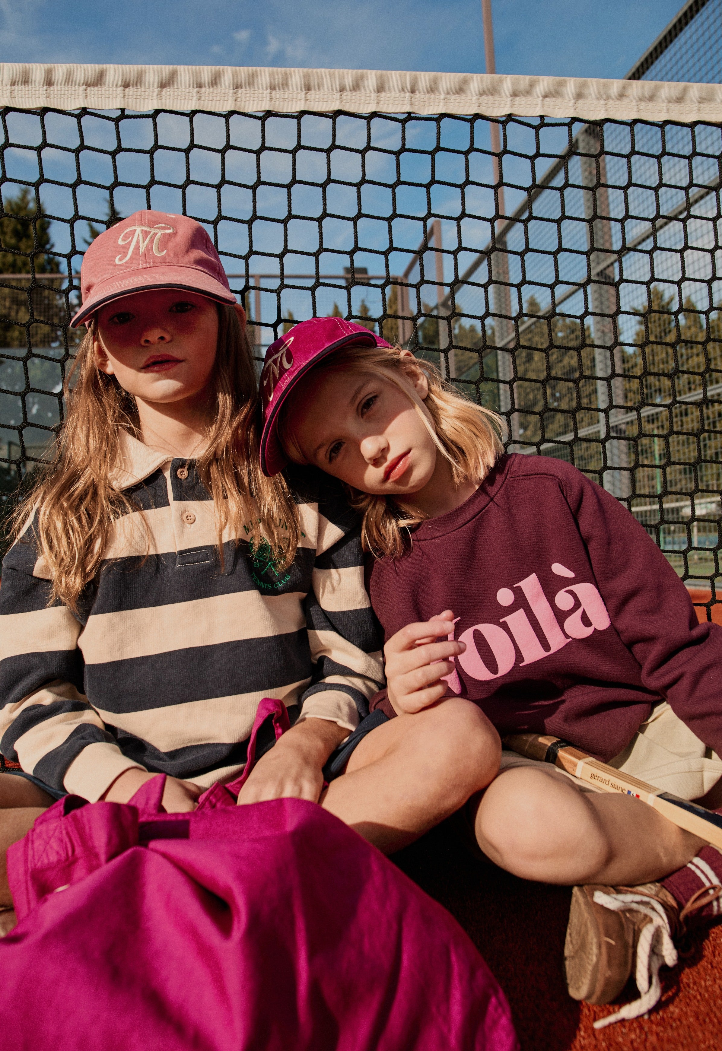 two girls wearing mipounet sweatshirts on a tennis court