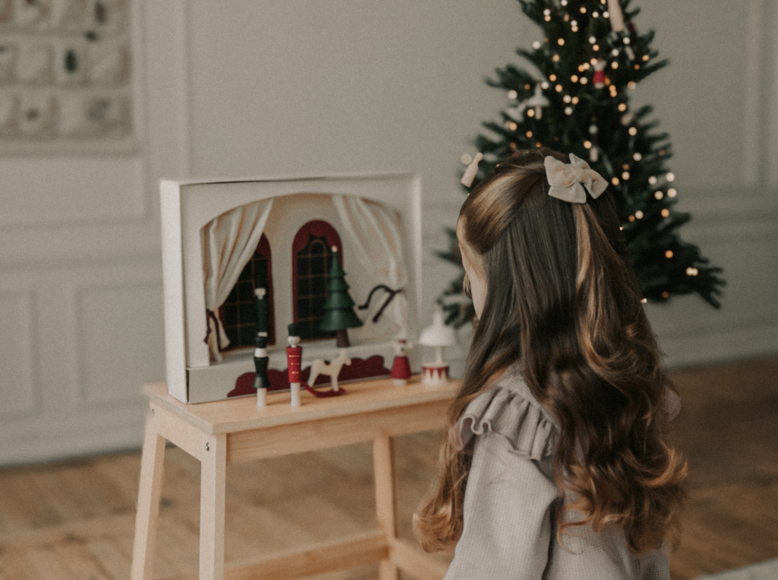 Child looking at a toy set on a stool with a Christmas tree in the background