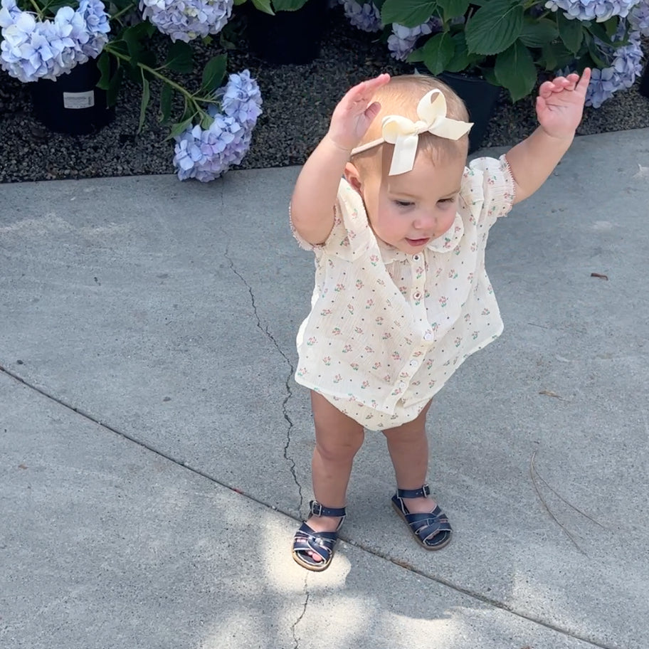 young baby girl with hands up wearing floral set