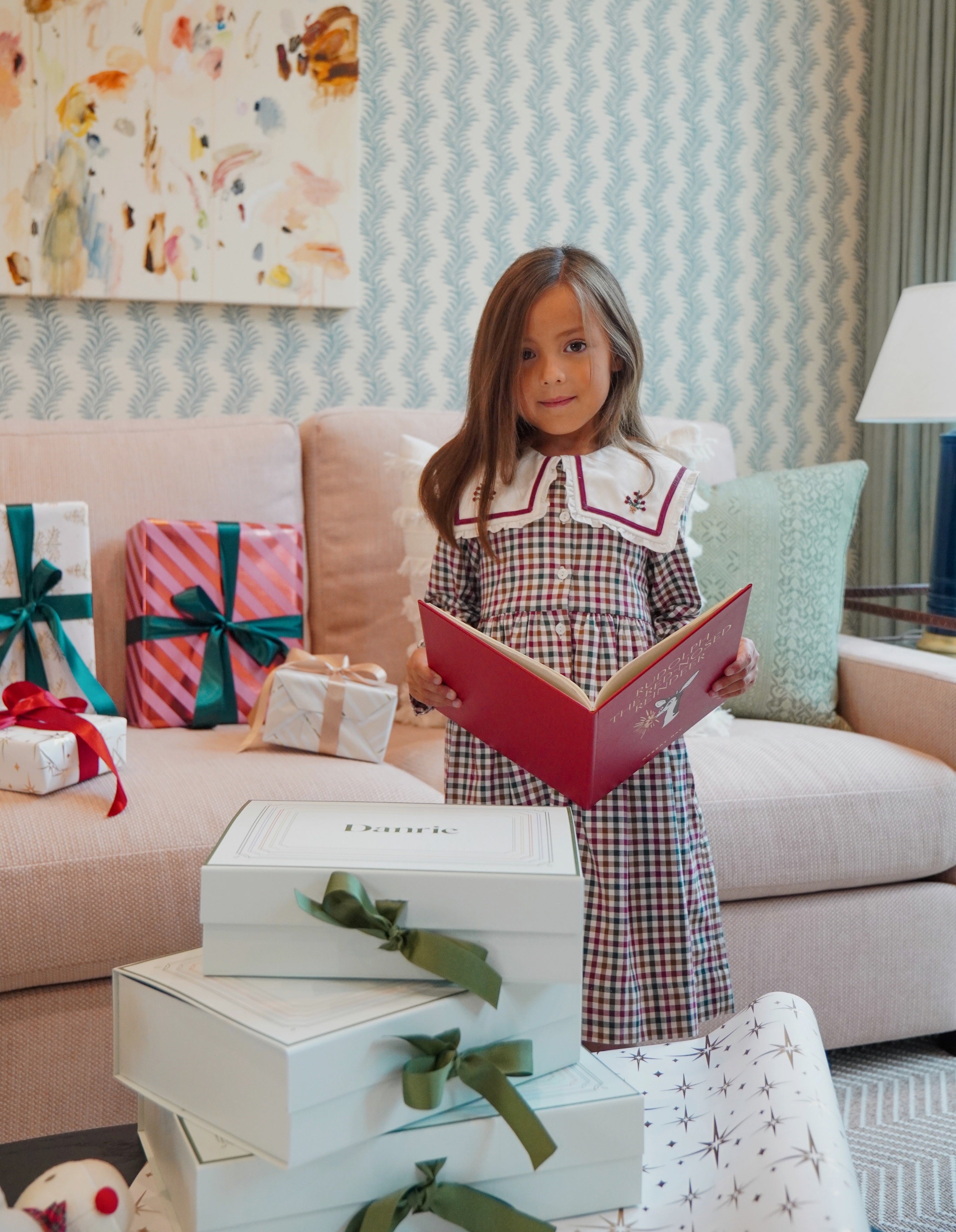 girl wearing holiday dress in front of danrie gift boxes