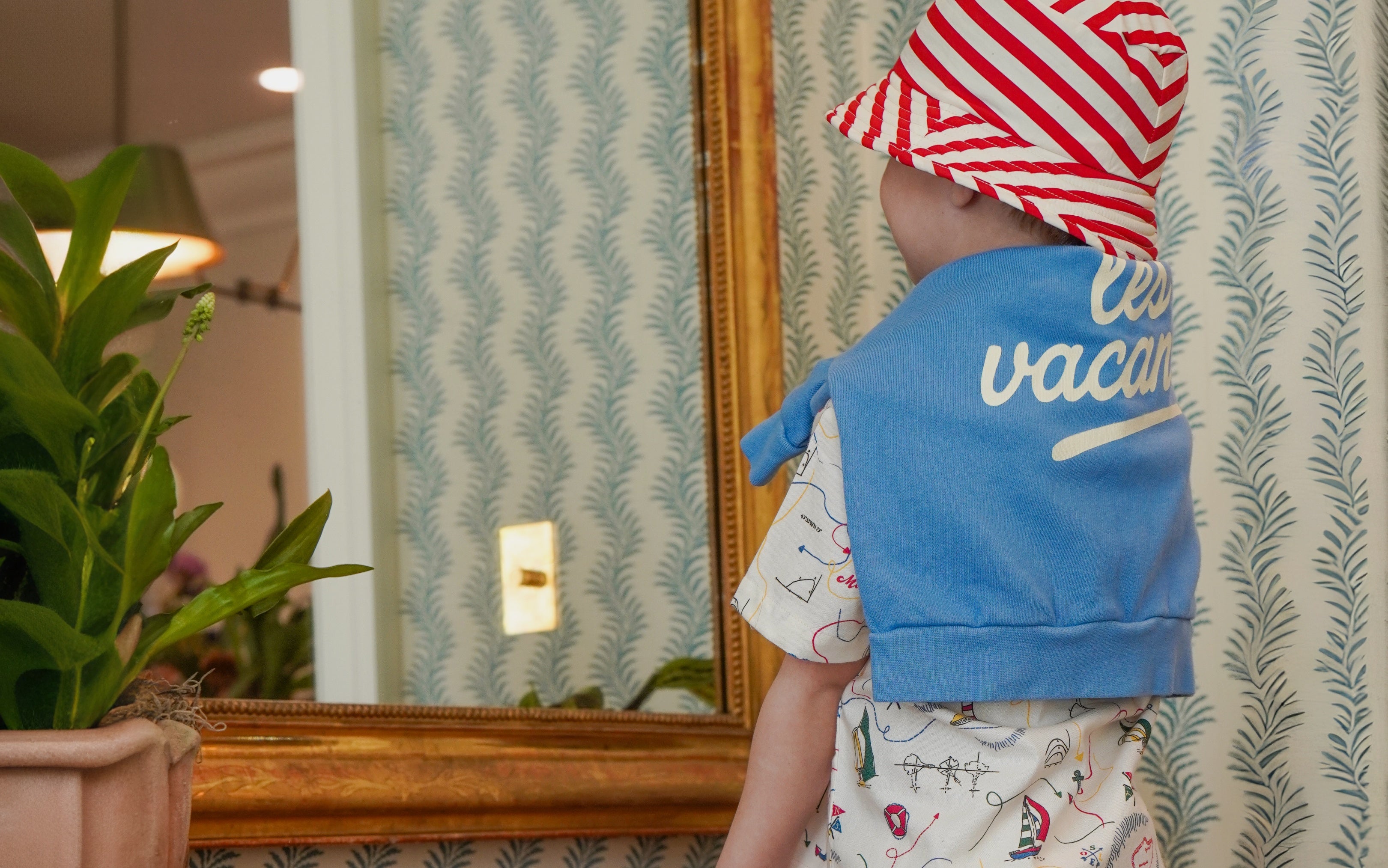 boy wearing les vacances sweatshirt looking in mirror